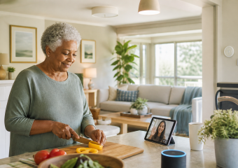Woman slices a yellow bell pepper while video chatting with someone on a tablet in her kitchen